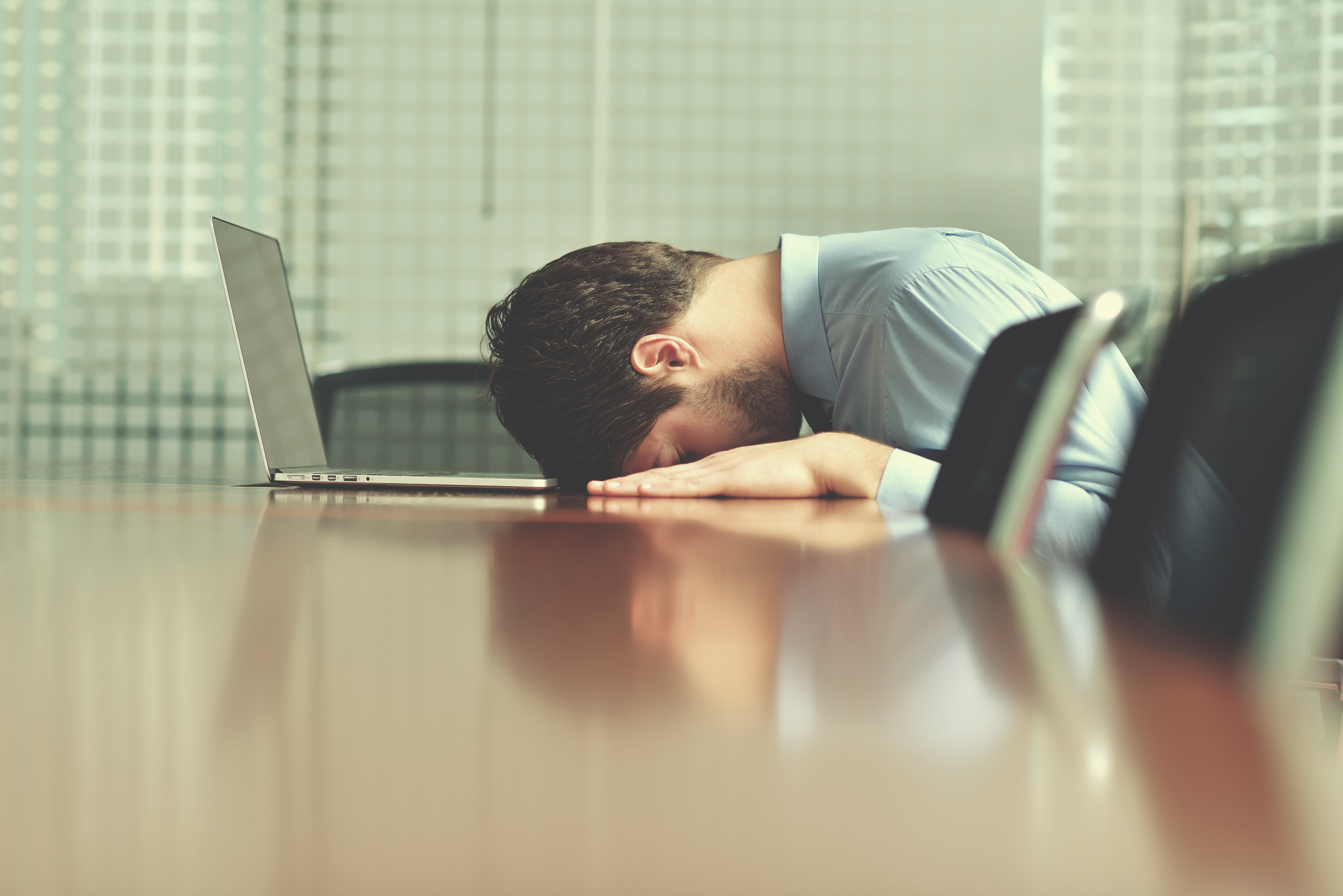 Stressed Businessman laying with head on desk in front of computer